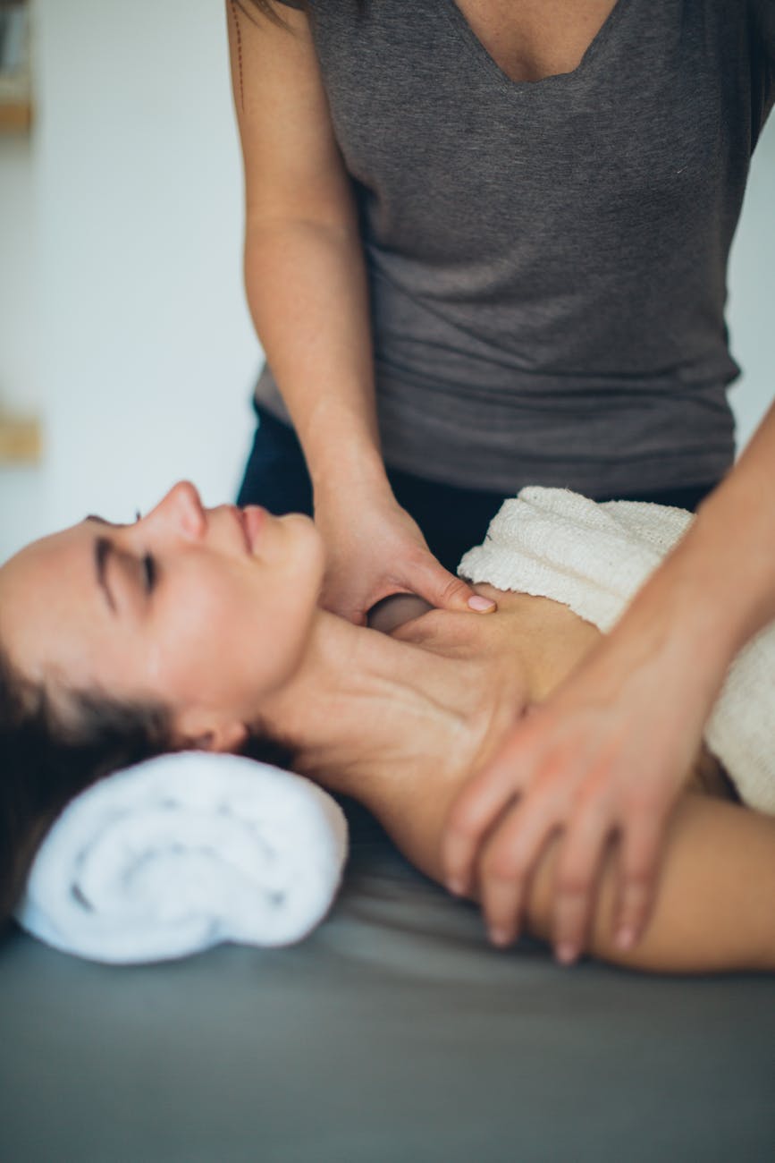 Sırt ve boyun masajı — havlu örtülü kadın müşterinin omuz ve trapez kaslarına spa dokunuşu